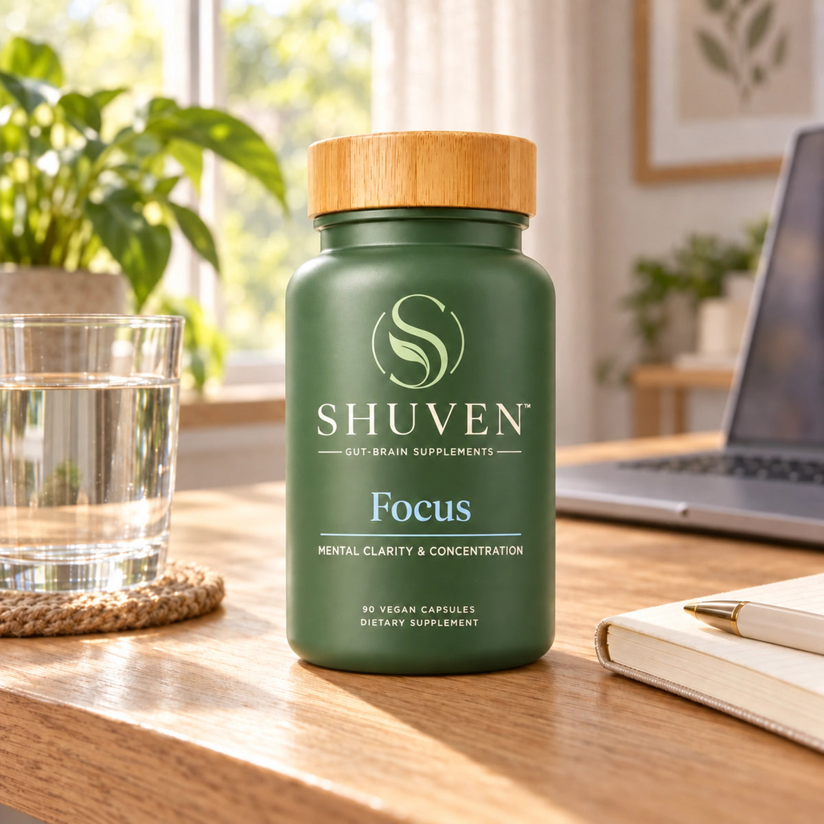 Shuven Focus supplement bottle on desk with water glass, notebook, and laptop