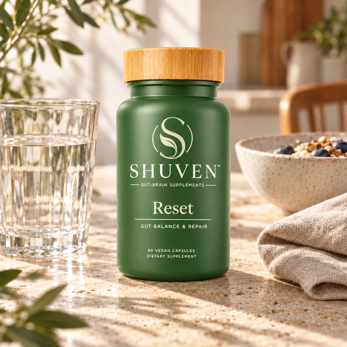 Shuven Reset supplement bottle on kitchen counter with water glass and breakfast bowl